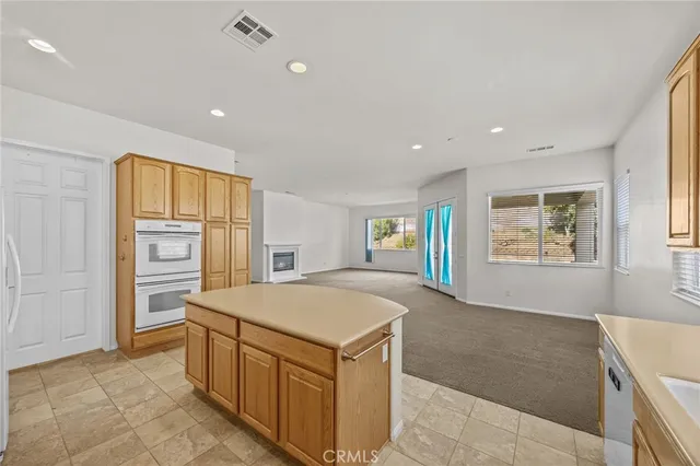 a view of an empty room with a window and a kitchen
