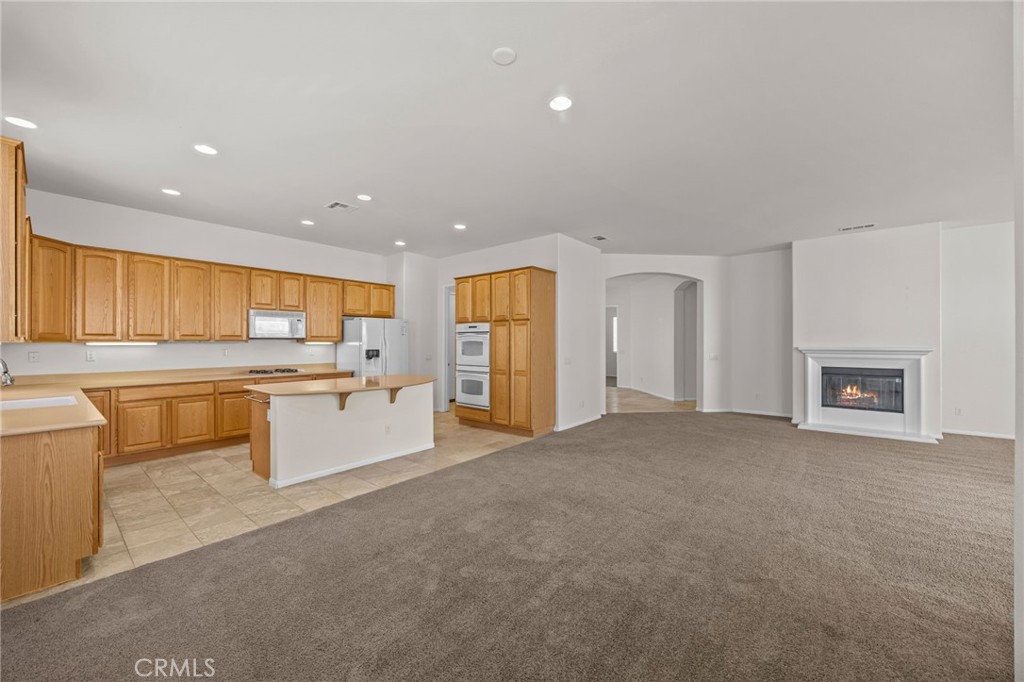 1140 Lantana Road Beaumont, CA 92223 - Photo 7 of 30 a large kitchen with kitchen island a sink white cabinets and stainless steel appliances