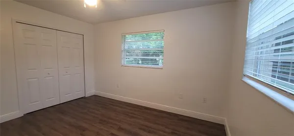 an empty room with wooden floor and window