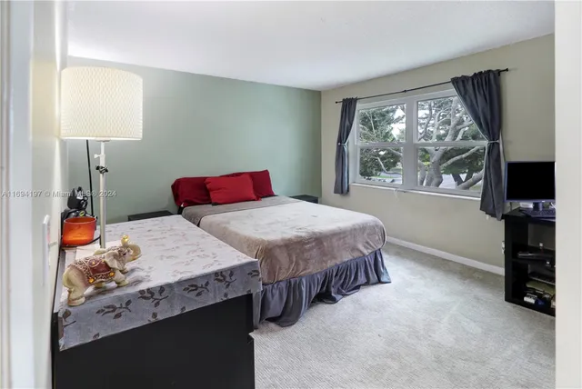 a bedroom with a bed and a flat tv screen on the dresser