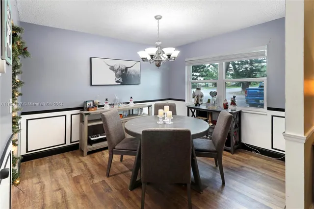 a view of a dining room with furniture a chandelier and wooden floor