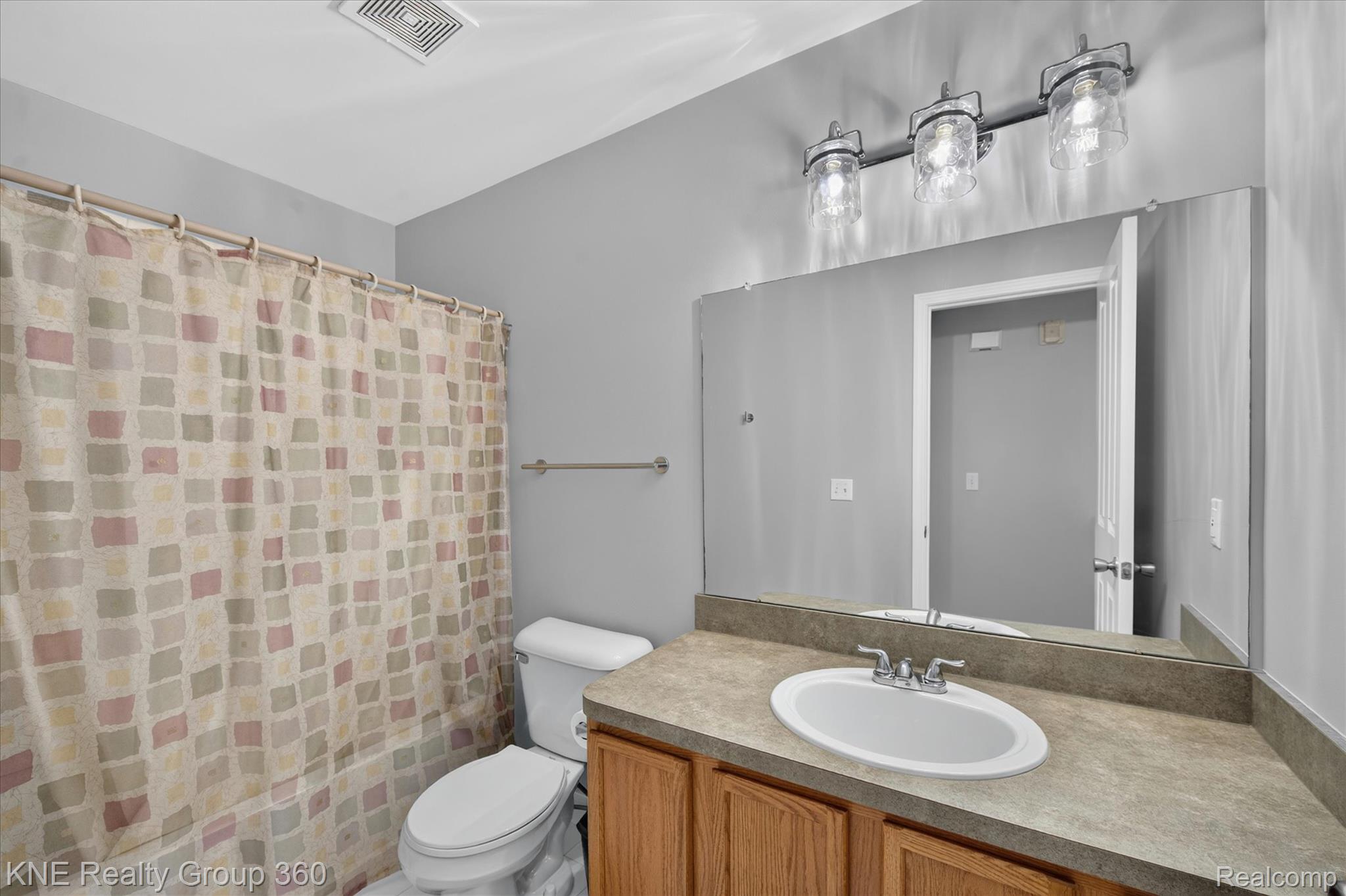 4077 Berkeley Avenue Canton, MI 48188 - Photo 22 of 32 Full bathroom featuring a single vanity with wood cabinetry, a large mirrored wall, and a three-light fixture