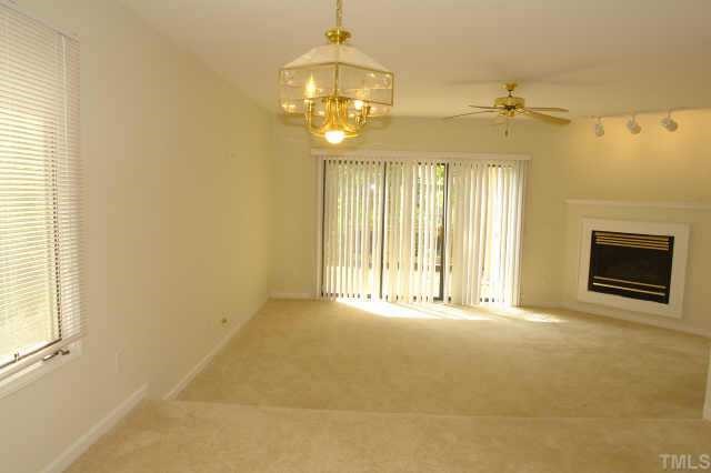 4211 Sunshadow Lane Raleigh, NC 27613 - Photo 6 of 10 a view of an empty room with a fireplace and a chandelier