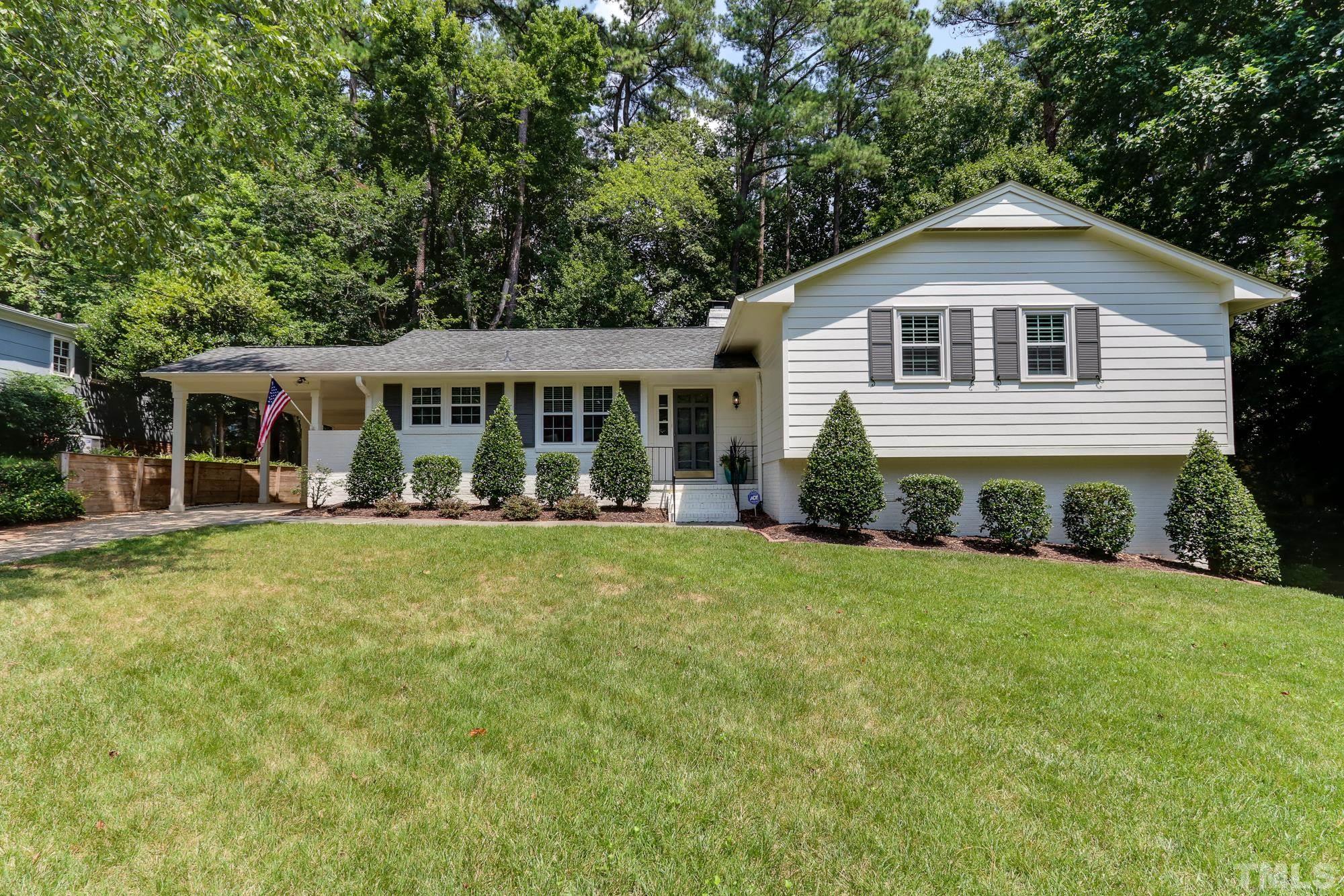a front view of a house with a yard and green space