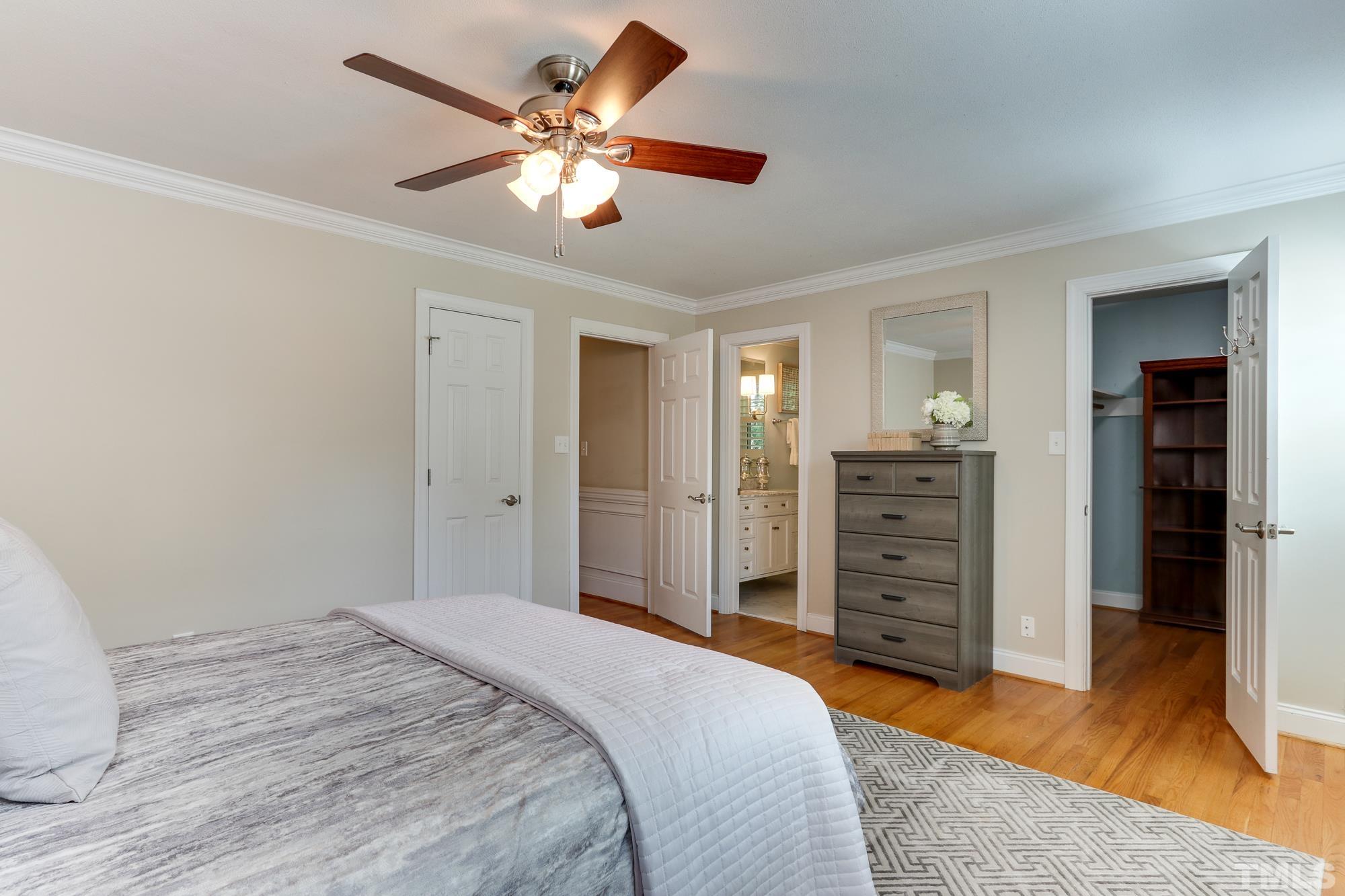 4804 Rampart Street Raleigh, NC 27609 - Photo 14 of 27 a spacious bedroom with a bed and a chandelier