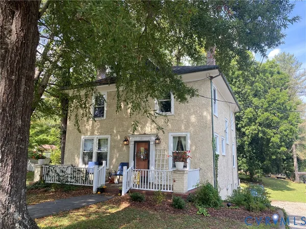 a view of a white house next to a yard with large trees