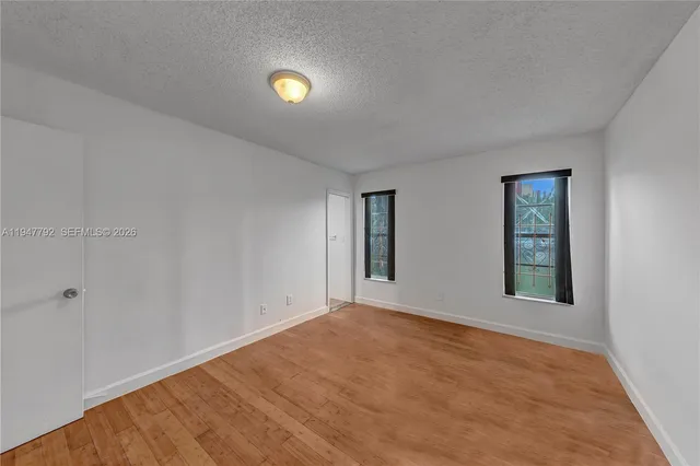 a view of an empty room with window and wooden floor