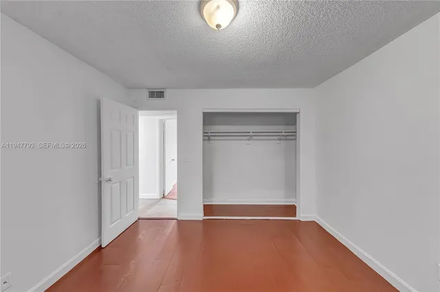 a view of an empty room with closet and a window