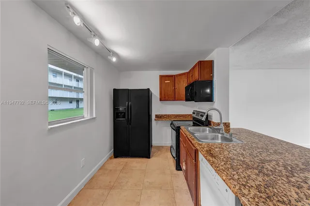 a kitchen with stainless steel appliances granite countertop a refrigerator a stove and a sink with wooden cabinets