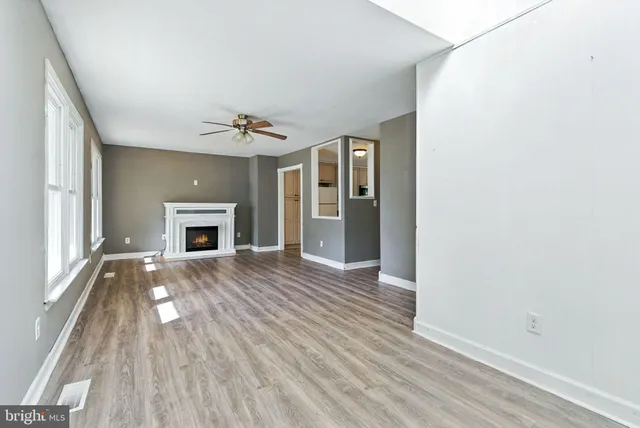 an empty room with wooden floor a fireplace and windows