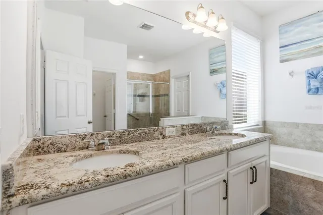 a bathroom with a granite countertop double vanity sink and mirror
