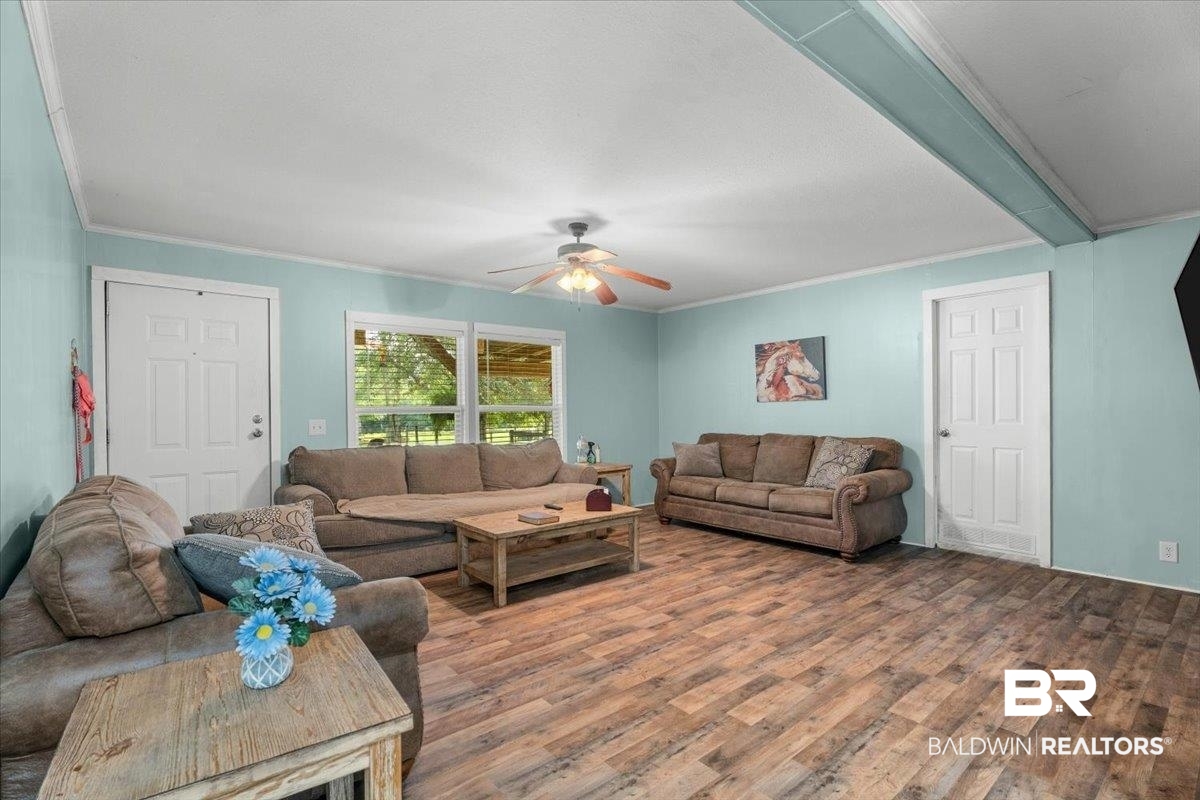 21011 River Road Robertsdale, AL 36567 - Photo 5 of 29 Spacious living area featuring wood-finish flooring, light blue walls, multiple windows, and a ceiling fan