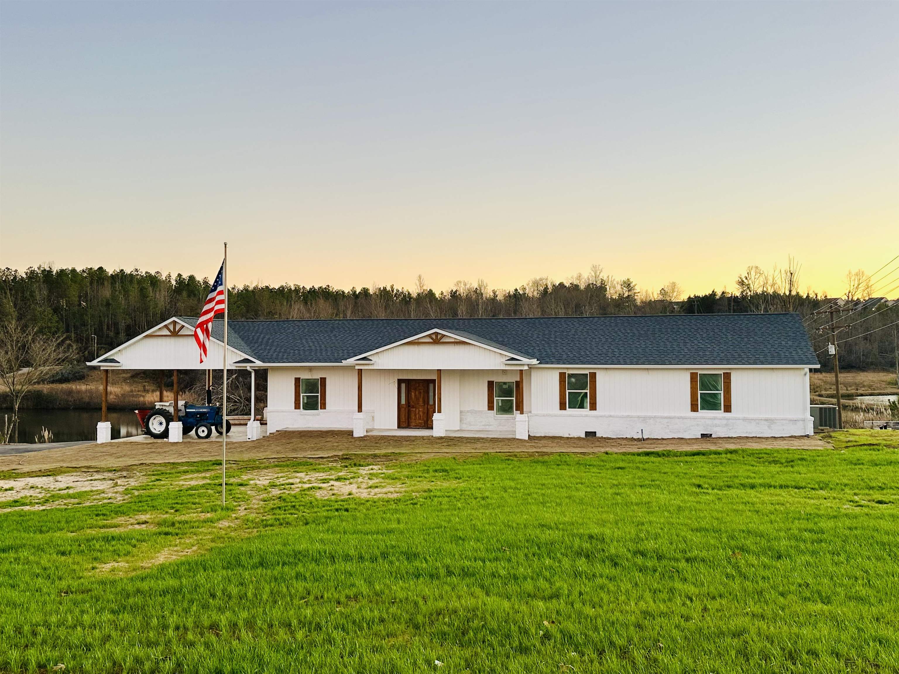 View of front of house with a lawn, a porch, and a carport