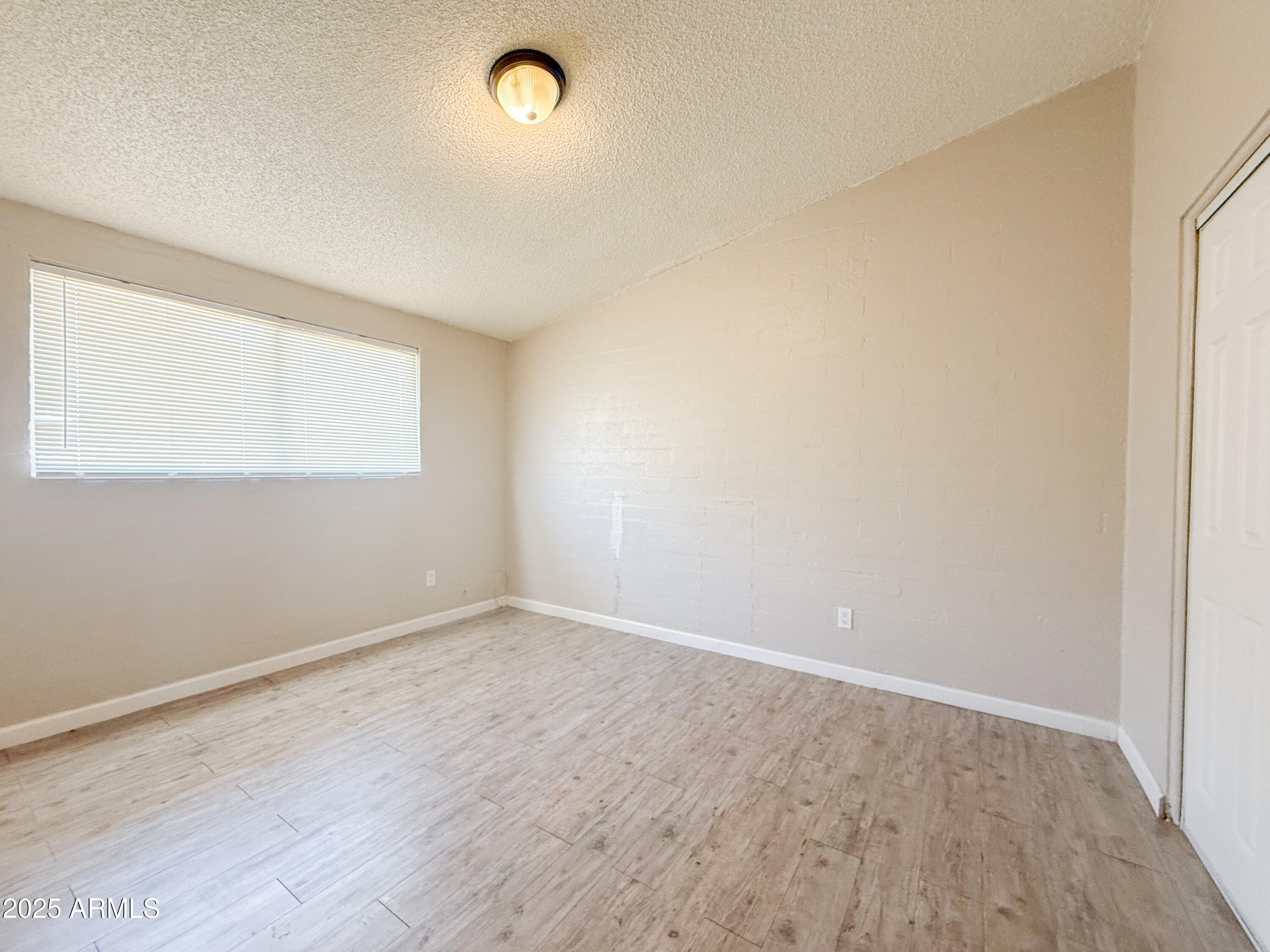 2123 West Devonshire Avenue, Unit 15 Phoenix, AZ 85015 - Photo 11 of 14 an empty room with wooden floor and windows