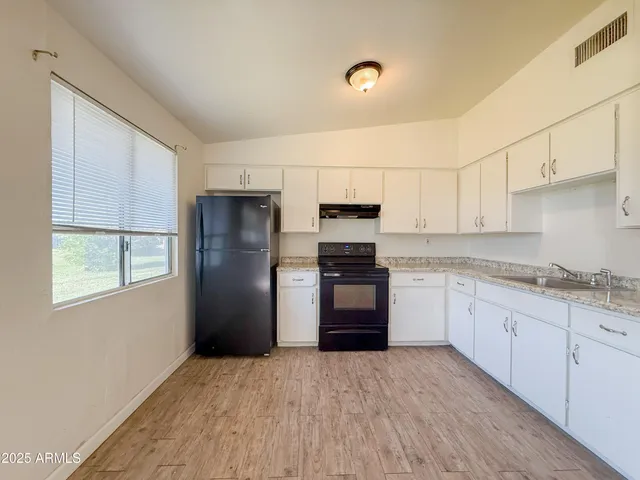 a kitchen with granite countertop a refrigerator and a stove top oven