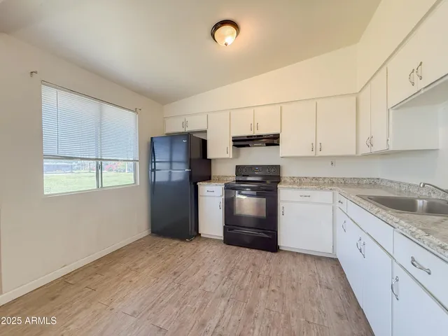 a kitchen with granite countertop a refrigerator and a stove top oven