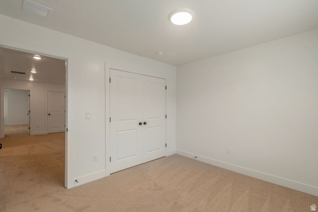 30 South Moonlit Road Mapleton, UT 84664 - Photo 15 of 25 Neutral-toned carpeted room featuring a double-door closet with black hardware, white baseboards, and a flush-mount ceiling light