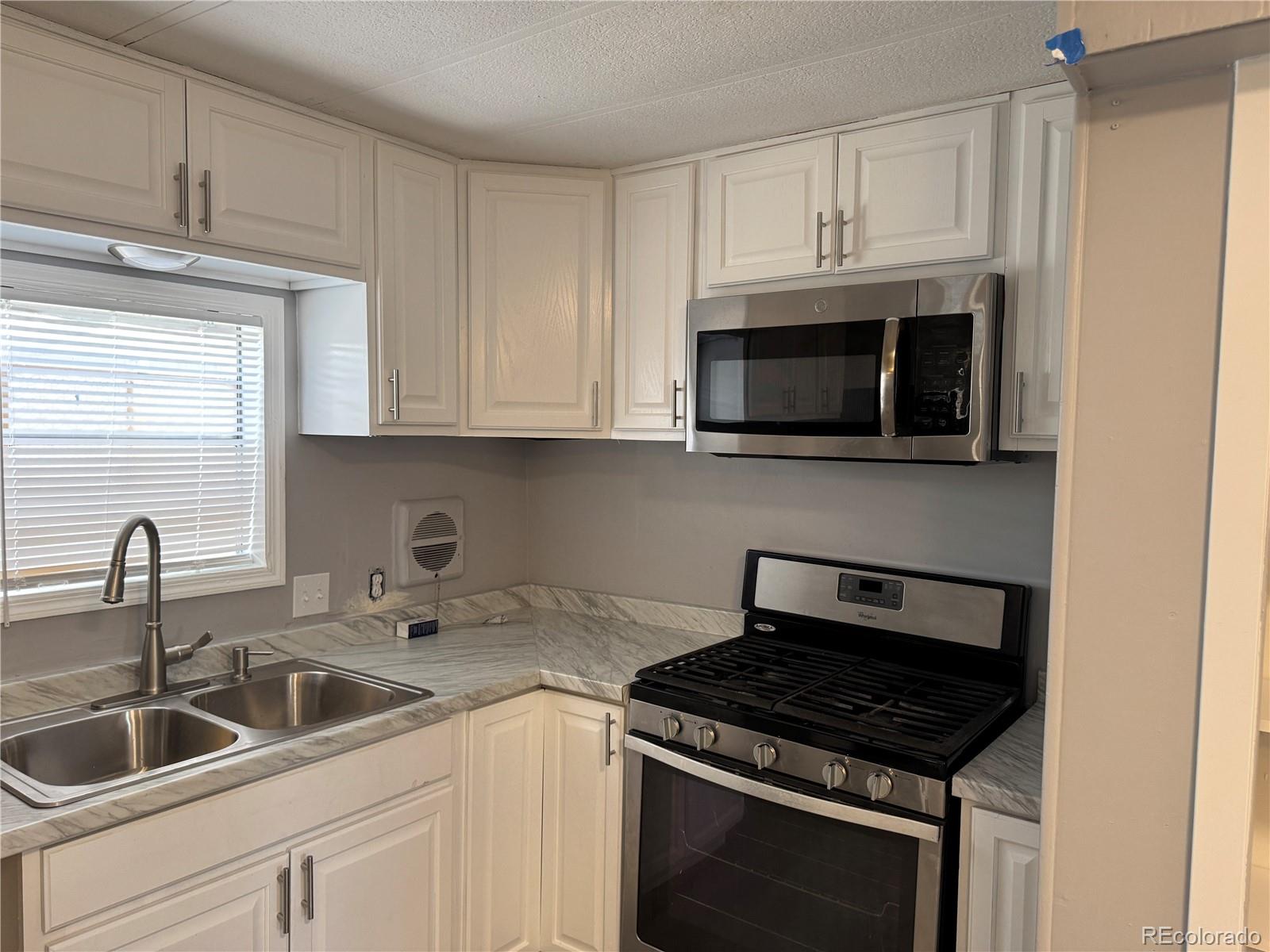 17190 Mt Vernon Road, Unit 176 Golden, CO 80401 - Photo 29 of 39 a kitchen with stainless steel appliances granite countertop white cabinets a microwave oven and a sink