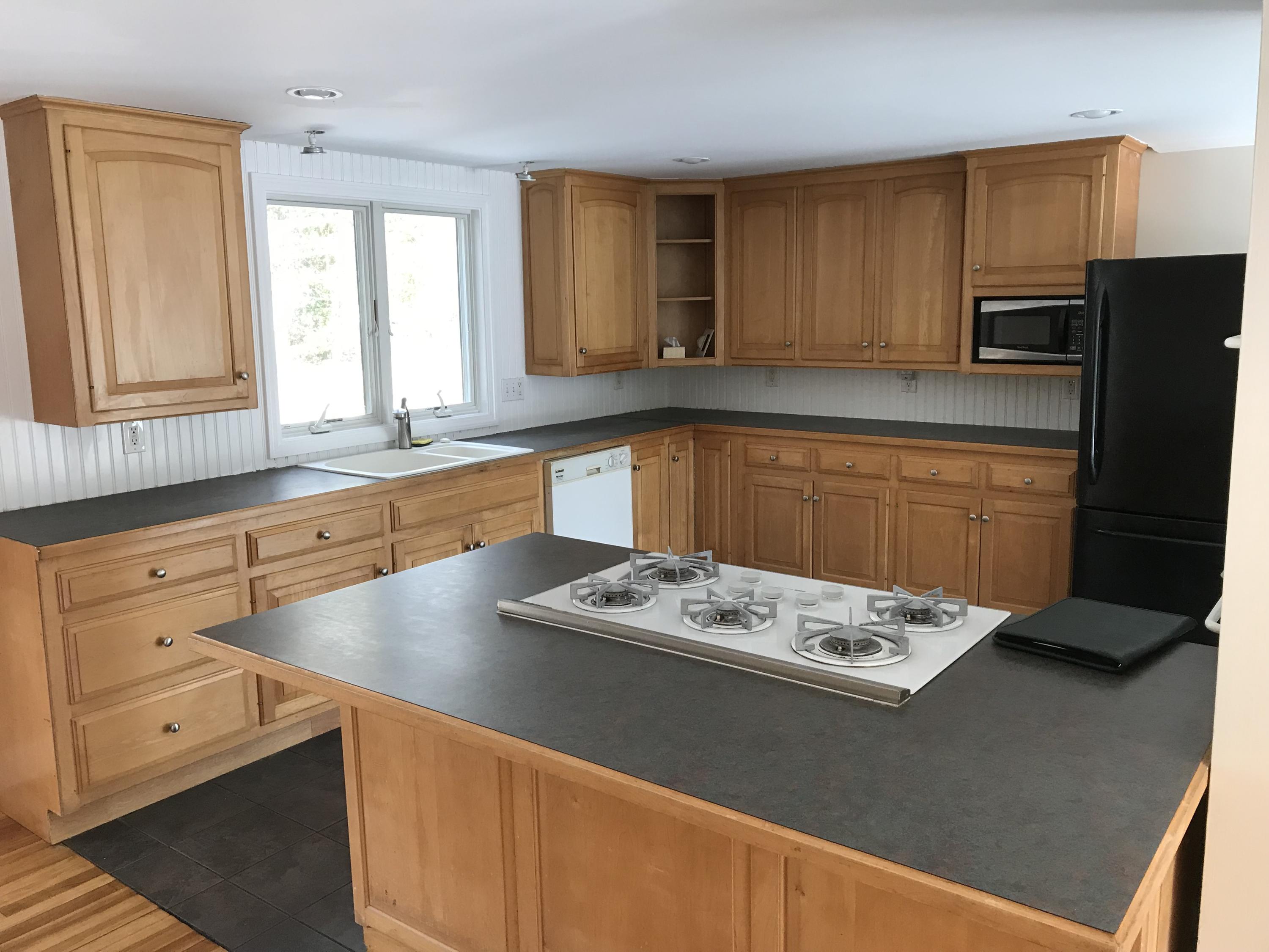 a kitchen with stainless steel appliances granite countertop a sink refrigerator stove and microwave