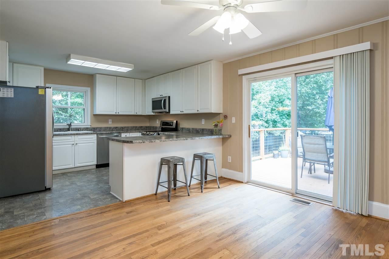 1234 Cross Link Road Raleigh, NC 27610 - Photo 8 of 26 a kitchen with kitchen island granite countertop a stove a refrigerator a sink a dining table and chairs with wooden floor