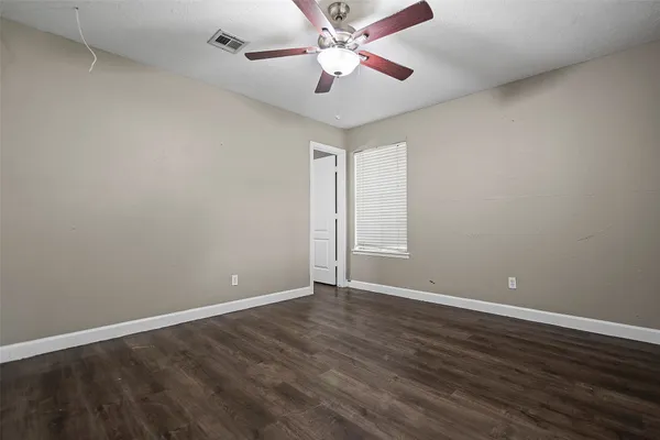 a view of an empty room with window and a ceiling fan