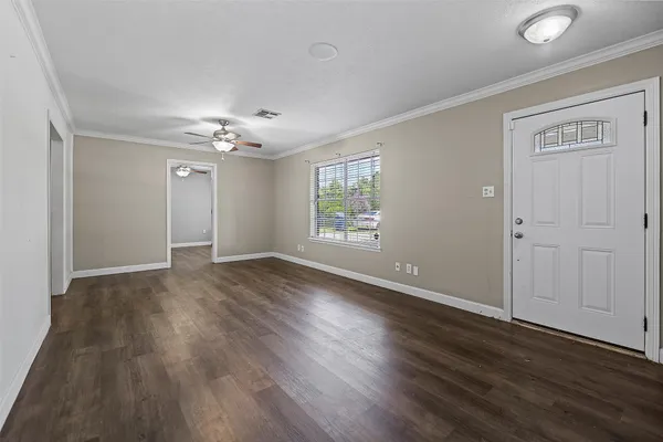 a view of an empty room with wooden floor and a window