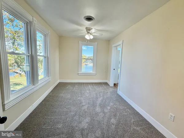 an empty room with windows and ceiling fan
