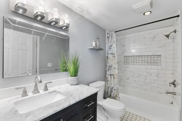 a bathroom with a granite countertop sink a toilet a mirror a vanity and shower