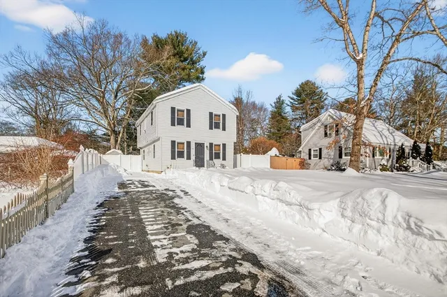 a view of a white house with a yard covered in snow