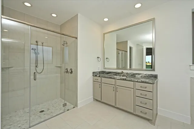 a bathroom with a granite countertop sink a mirror and a shower