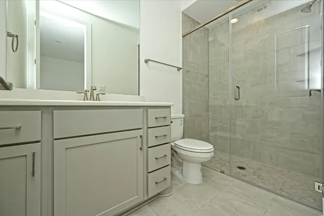 a bathroom with a shower sink vanity and toilet