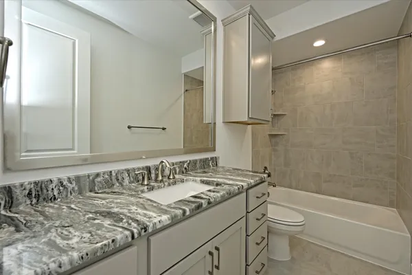 a bathroom with a granite countertop sink a toilet and shower