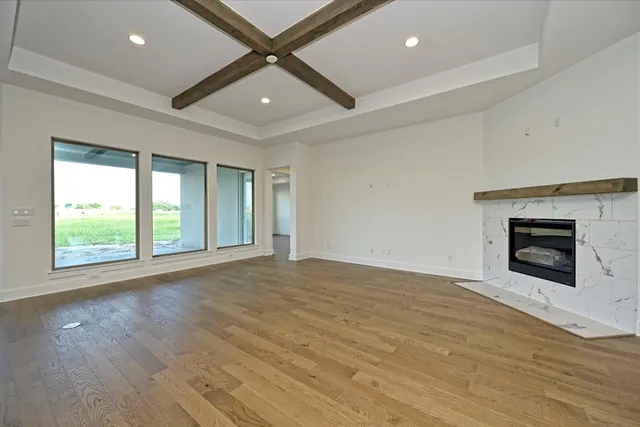 an empty room with wooden floor fireplace and windows