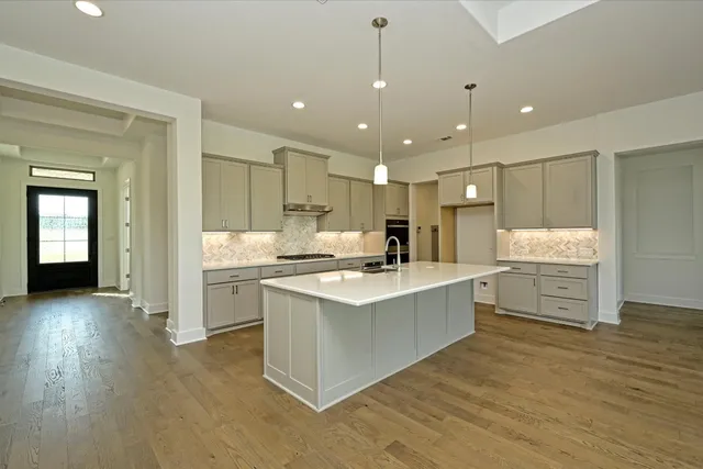 a large white kitchen with kitchen island a sink stainless steel appliances and cabinets
