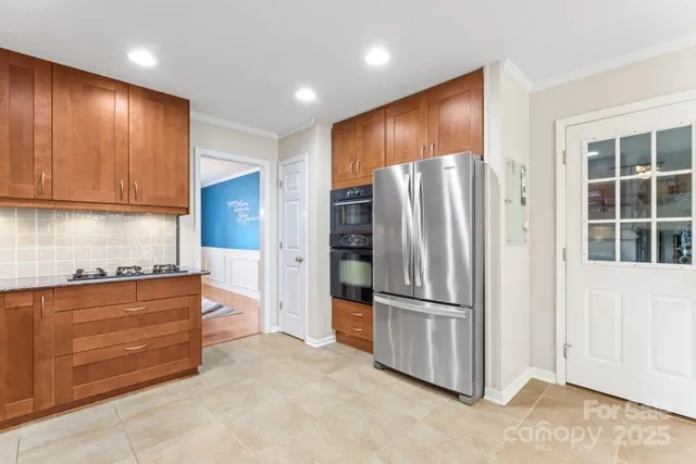 a kitchen with stainless steel appliances granite countertop a refrigerator and a stove top oven