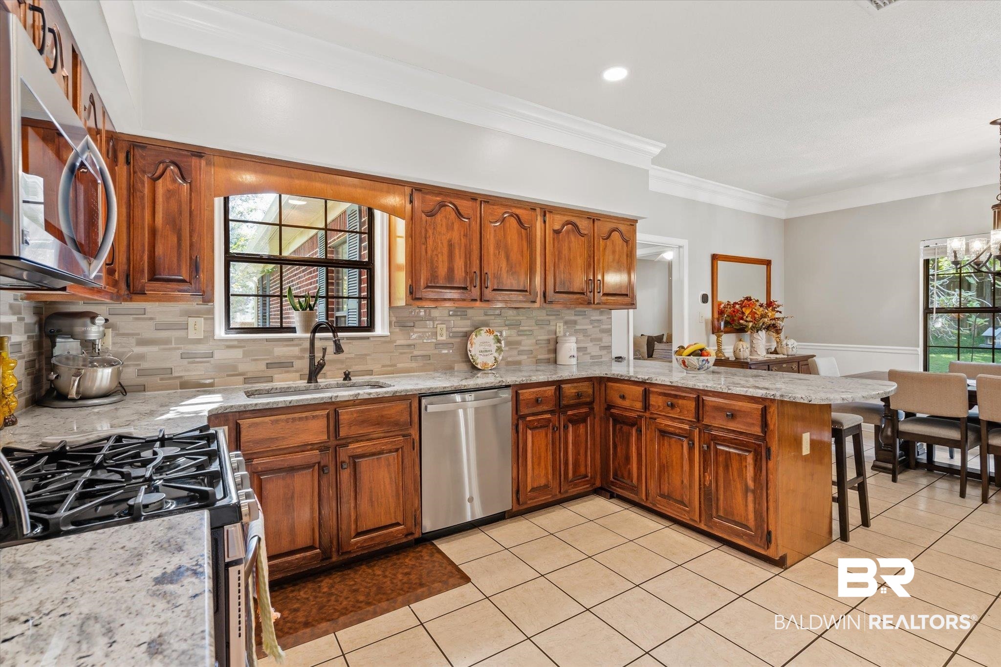 7360 Bridgewood Court Mobile, AL 36695 - Photo 7 of 30 Kitchen with stainless steel appliances, tasteful backsplash, sink, kitchen peninsula, and ornamental molding