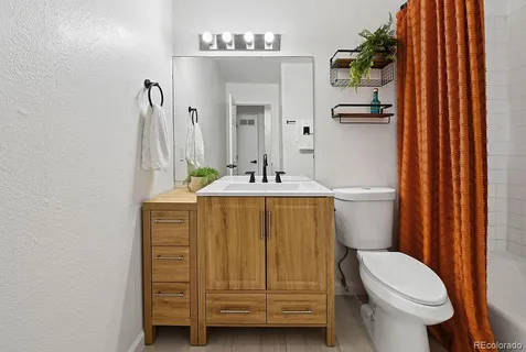 a bathroom with a sink a toilet a mirror and shower curtain