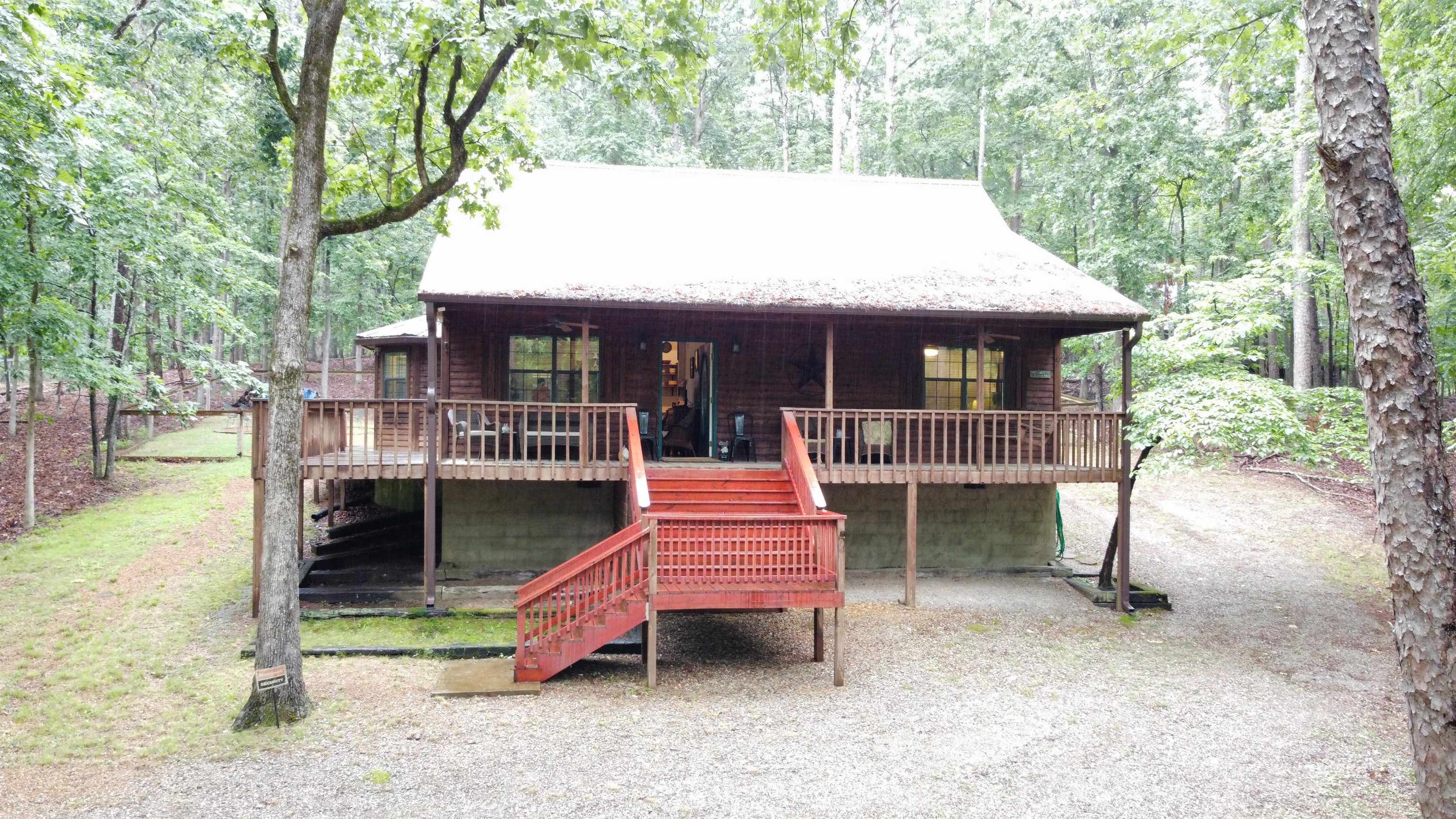 Wood-sided cabin-style residence featuring a prominent red-painted outdoor staircase and a spacious elevated wooden deck