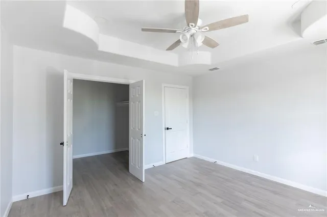 an empty room with wooden floor ceiling fan and closet area