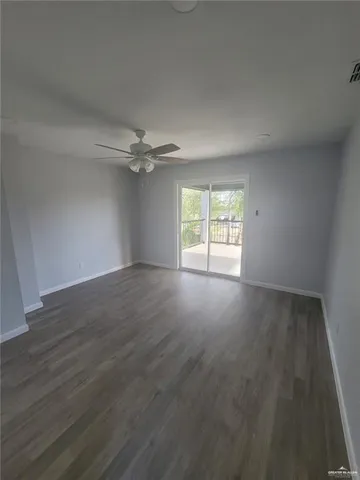 an empty room with wooden floor fan and windows