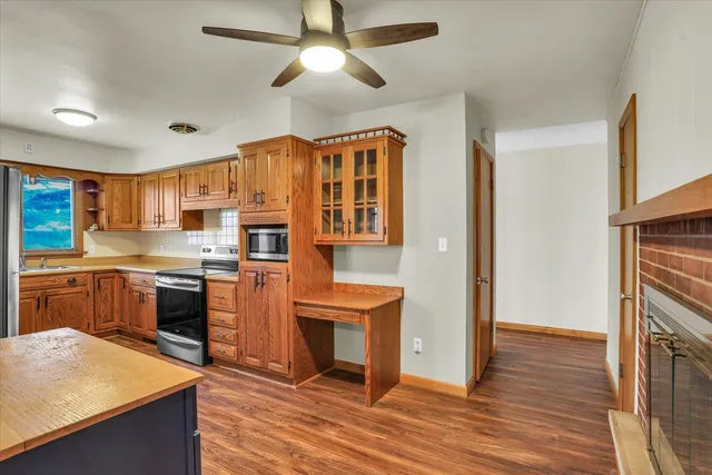 a kitchen with stainless steel appliances granite countertop a refrigerator a sink dishwasher a stove and white countertops with wooden floor