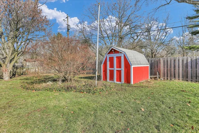 a view of backyard with large tree and wooden fence