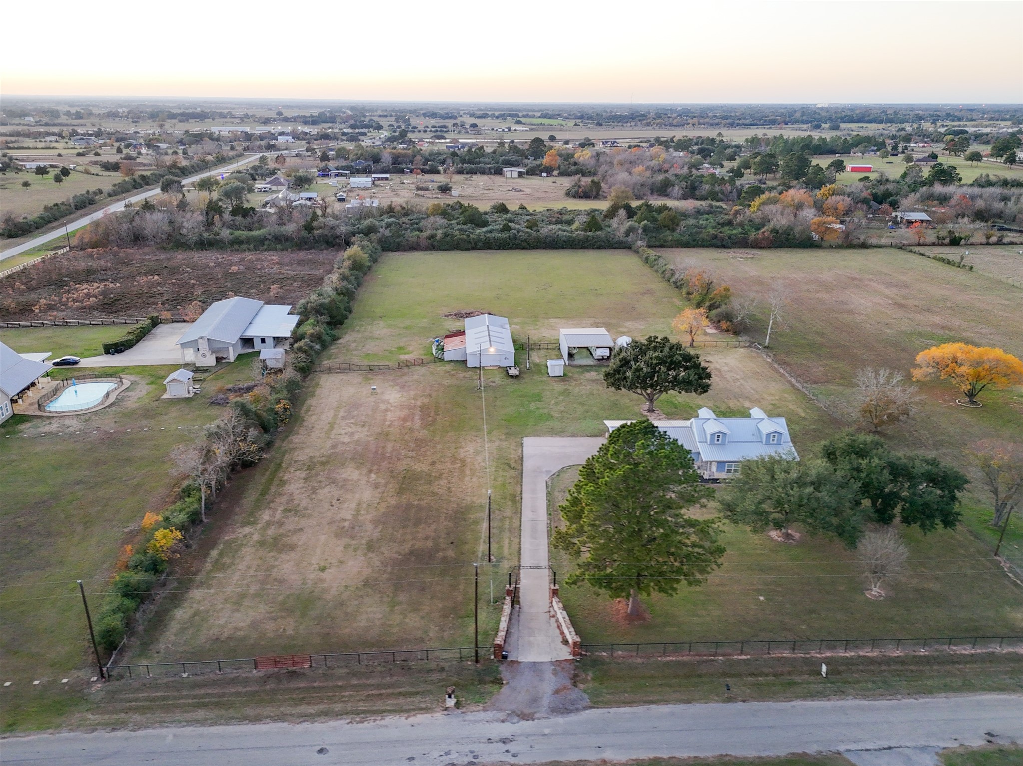 19989 Meadow Bend Road Hempstead, TX 77445 - Photo 28 of 35 Elevated aerial view showcasing the home, gated entrance, barn, and fenced pasture with surrounding open land.