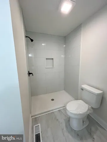 a white toilet sitting next to a bathroom sink and a shower