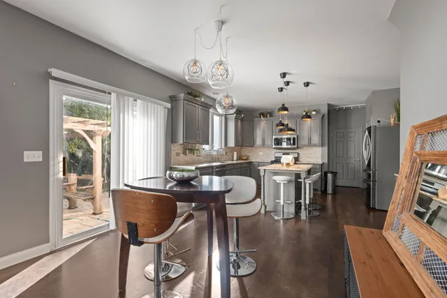 a dining room with wooden floor a chandelier a wooden table and chairs