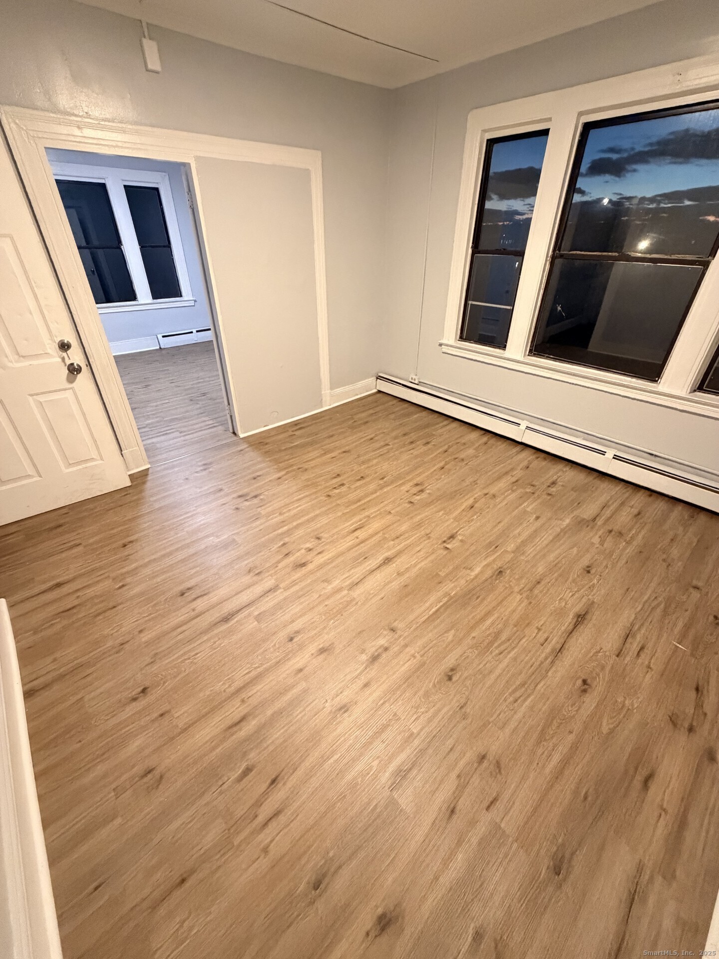 a view of an empty room with wooden floor and staircase