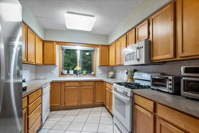 a kitchen with stainless steel appliances granite countertop white cabinets granite counter tops and a window