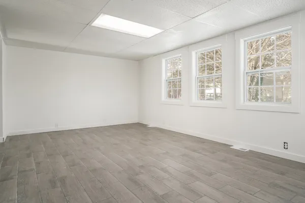 an empty room with wooden floor and windows