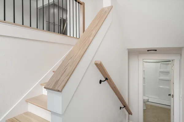 a view of staircase with white walls and railing