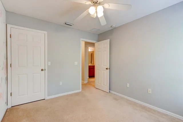 a view of an empty room and chandelier fan